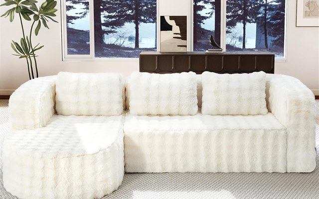 White faux-fur sectional sofa facing a snowy forest window